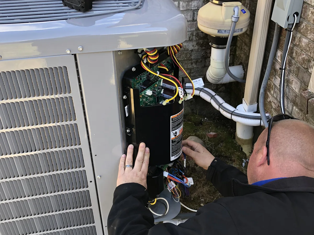 A.J. LeBlanc Heating HVAC technician servicing an outdoor condenser in Southern NH