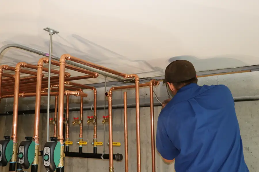 A.J. LeBlanc Heating technician installing a copper hydronic manifold and zone circulators for a new home boiler system in Southern NH