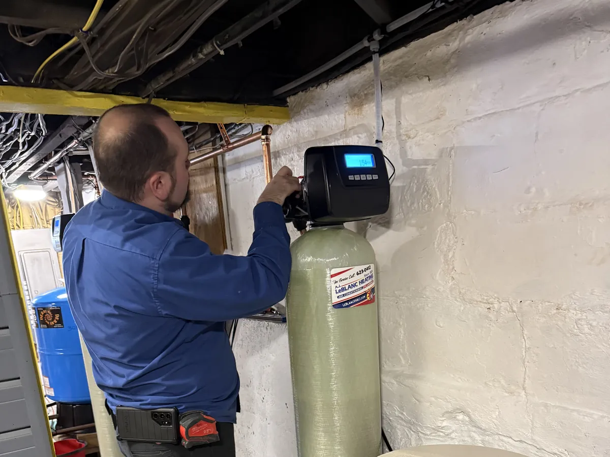 A.J. LeBlanc Heating technician programming the digital control head on a whole-house water filtration tank during a service call in Southern NH